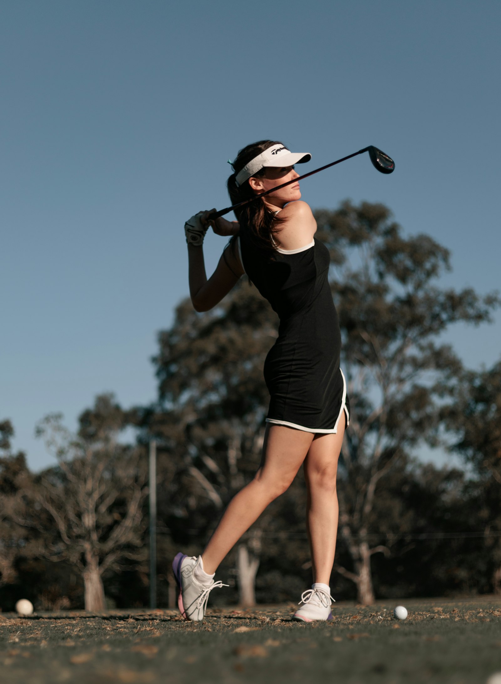 A woman amateur swinging at a golf ball